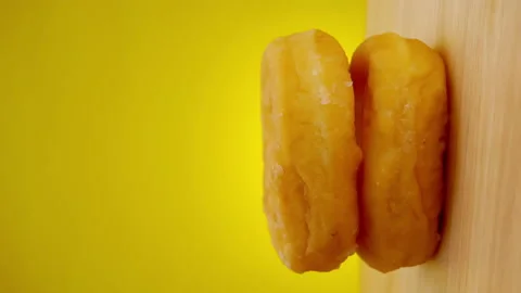 Stack of donuts on a rotating wooden plate with yellow background. Stock Footage 147737472