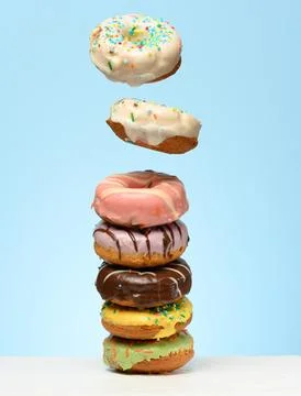 A stack of donuts with various fillings and glazes, several levitating upward Stock Photos