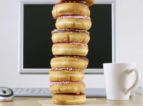 Stack of Doughnuts in front of computer. Stock Photos