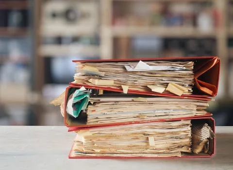 Stack of dusty messy file folders with narrow depth of field, blurred offic.. Stock Photos