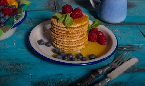 Stack of Dutch caramel waffles with raspberries, blueberries and honey on blu Stock Photos