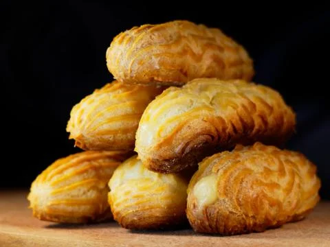 A stack of eclairs without glaze. Eclairs on a wooden background. Stock Photos