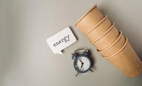 Stack of eco-friendly paper cups beside a vintage alarm clock and a speech Stock Photos