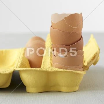 A Stack Of Egg Shells In A Yellow Egg Box