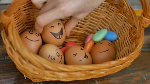 Stack of eggs with hand drawn faces on straw basket with colorful candy, easter Video stock 151410741