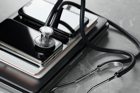Stack of electronic devices and stethoscope on grey table, closeup Stock Photos