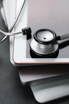 Stack of electronic devices and stethoscope on black table, closeup Foto stock