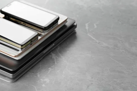 Stack of electronic devices on grey stone table, closeup. Space for text Stock Photos