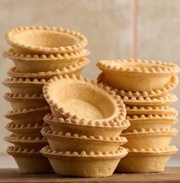 Stack of empty baked round canape baskets on a wooden board, round empty ta.. Stock-Fotos