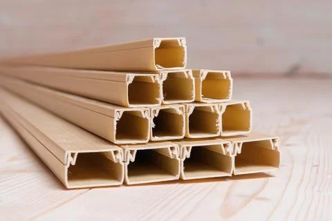 Stack of empty beige plastic cable channels arranged in a pyramid on a wooden Foto stock