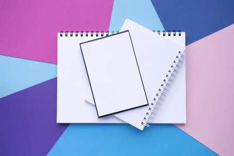 Stack of empty blocks and notebooks with a spiral. Pink, blue paper background Stock Photos