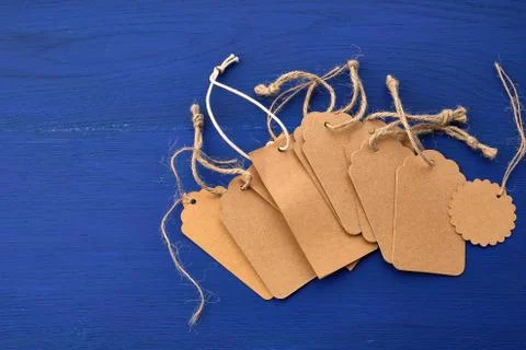 Stack of empty brown empty tags from kraft paper with ropes for clothes and o 스톡 사진
