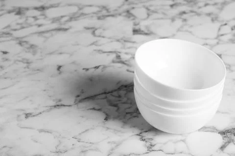 Stack of empty ceramic bowls on white marble table, space for text 스톡 사진