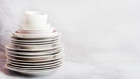 Stack of empty clean plates on a gray table with copy space. Stock Photos