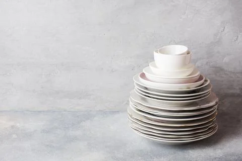 Stack of empty clean plates on a gray table with copy space. Stock Photos