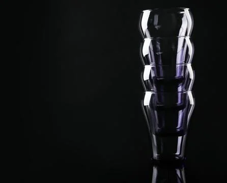 Stack of empty colorful glasses on black background, space for text 写真素材