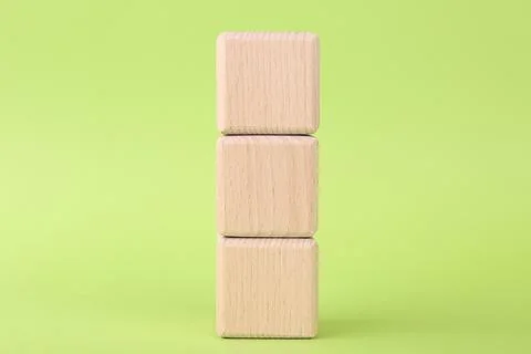 Stack of empty wooden cubes on light green background Stock Photos