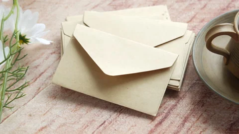 Stack of envelope , flower and cup of tea on table Stock Footage 167457447