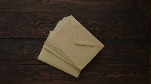 A stack of envelopes falls on a brown wooden table, top view Stock Footage 259063000