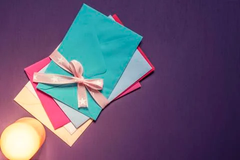 Stack of envelopes tied with bow in candlelight 写真素材