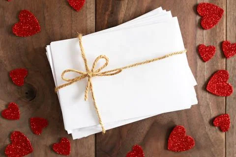 Stack of Envelopes tied with Twine Bow Surrounded by Heart Shapes on Wood B.. Foto stock