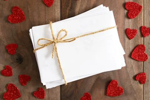 Stack of Envelopes tied with Twine Bow Surrounded by Heart Shapes on Wood B.. Foto stock