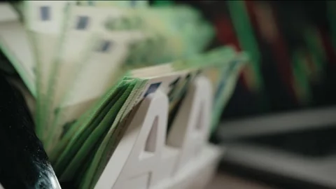 Stack of euro banknotes displayed in a money holder on a desk, with a laptop and Stock Footage 331079620