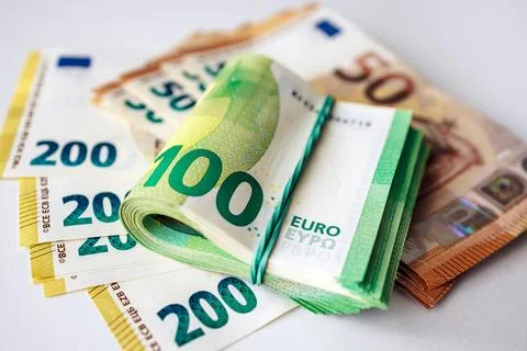 Stack of Euro banknotes including a rolled bundle of 100 Euro notes on a wh.. Foto stock