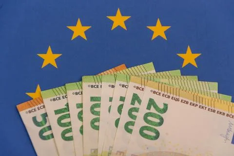 A stack of euro banknotes is placed against the flag of the European Union Stock Photos