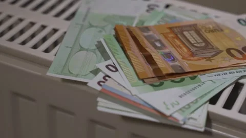 Stack of euro banknotes placed on a radiator highlighting rising heating costs Stock Footage 324521917
