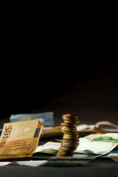 Stack of euro coins and banknotes in a black background Stock Photos