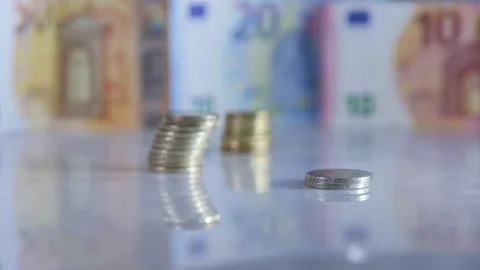 Stack of euro coins growing smaller against backdrop of euro bills. Stock Footage