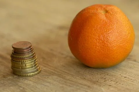 Stack of euro coins next to a fresh mandarin orange Stock Photos