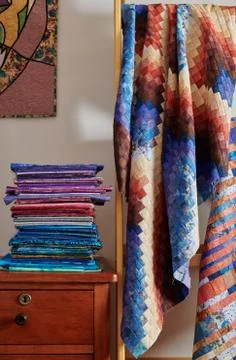 Stack of fabrics and quilt made in the bargello style on white wall backgroun Stock-Fotos