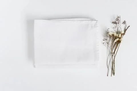 Stack of fabrics with dry flowers over light background. Flat lay with whit.. Fotos Stock