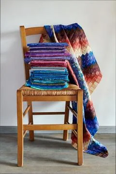 Stack of fabrics lying on chair and quilt top made in bargello style Fotos Stock