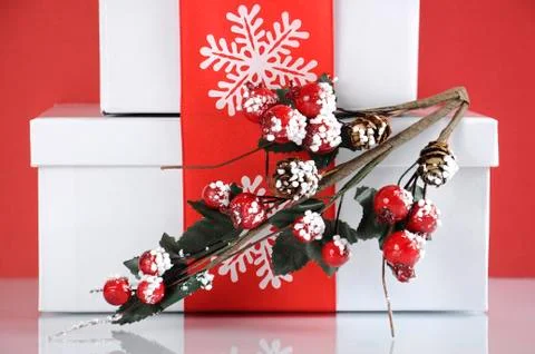 Stack of festive red and white theme Christmas gift boxes on reflective white Stock Photos