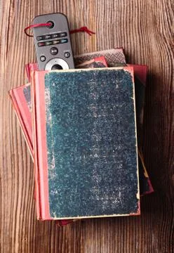 Stack a few books on wooden table with bookmark in shape of tv remote inserte Foto stock