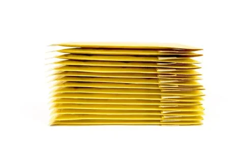 Stack of fifteen yellow bubble envelopes isolated on white. Side view. Foto stock