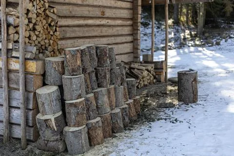 Stack of firewood logs outside a rustic log cabin in winter snow Fotos de archivo