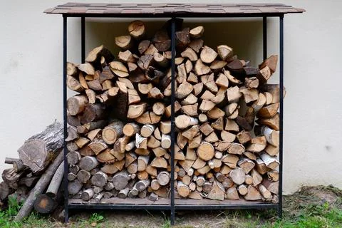 A stack of firewood in the yard against a white wall Stock Photos