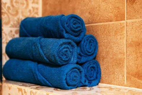 A stack of five bath blue towels rolled up on a shelf in the bathroom Stock Photos