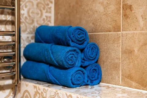 A stack of five bath blue towels rolled up on a shelf in the bathroom Stock Photos