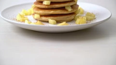 Stack of fluffy pancakes with banana slices on a white plate Stock Photos