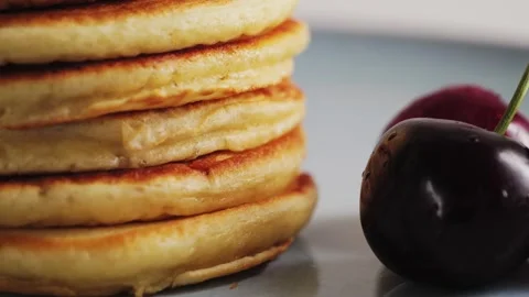 Stack of fluffy pancakes with maple syrup or honey and cherry. Concept of a Stock Footage 330117028