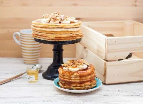 Stack of fluffy pancakes with maple syrup, banans, jam and nuts. Rustic woode Stock Photos