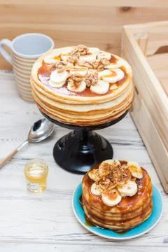 Stack of fluffy pancakes with maple syrup, banans, jam and nuts. Rustic woode Stock Photos