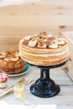 Stack of fluffy pancakes with maple syrup, banans, jam and nuts. Rustic woode Stock Photos