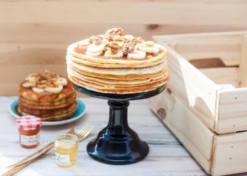 Stack of fluffy pancakes with maple syrup, banans, jam and nuts. Rustic woode Stock Photos