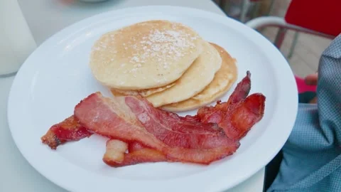 Stack of Fluffy Pancakes with Powdered Sugar and Strips of Crispy Bacon Stock Footage 345927441
